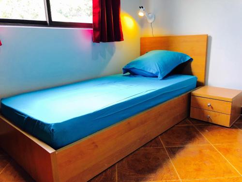 a bed with a blue pillow and a window at La Kaza du Soleil in Tarrafal