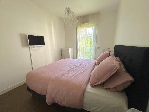 - une chambre avec un lit avec des draps roses et une fenêtre dans l'établissement L'appartement Saussure, à Paris