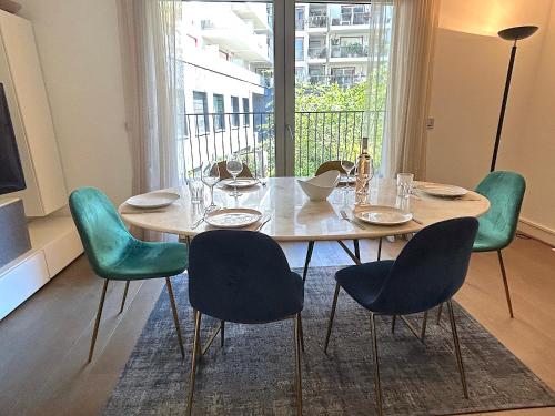 une table de salle à manger avec des chaises et une grande fenêtre dans l'établissement L'appartement Saussure, à Paris