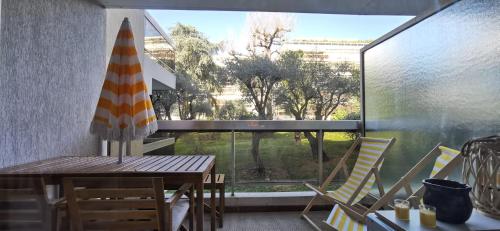 d'une terrasse avec une table et un parasol sur le balcon. dans l'établissement Escale en Méditerranée, swimmingpool, terrace,AC, à Antibes