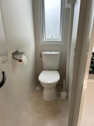Elle comprend une petite salle de bains pourvue de toilettes et d'une fenêtre. dans l'établissement Mobil home 2 chambres, à Verneuil-sur-Seine
