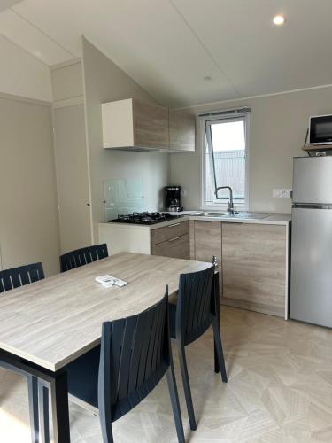 une cuisine avec une table, des chaises et un réfrigérateur dans l'établissement Mobil home 2 chambres, à Verneuil-sur-Seine