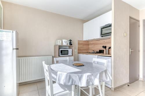 - une cuisine avec une table blanche et des chaises blanches dans l'établissement GuestReady - Sleek & Sunny Comfort near the Tram, à Lyon