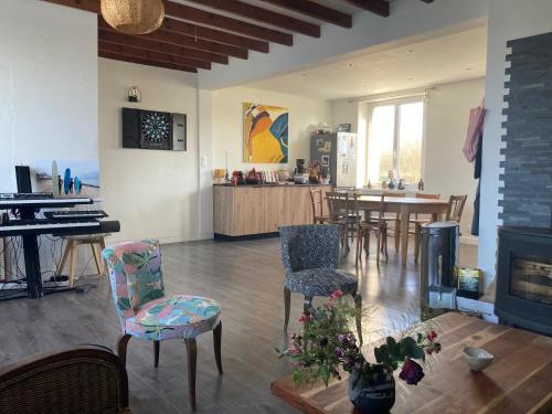 a living room with a piano and chairs and a table at La Maison de Marin in Surtainville
