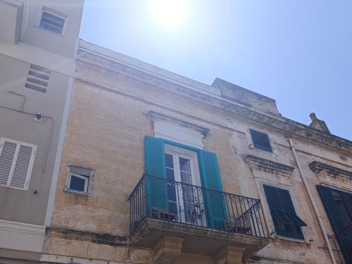 an old building with blue shutters and a balcony at Sweet House Monopoli in Monopoli