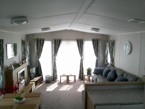 a living room with a couch and a large window at Mayville Parkstone 6 Berth Central heated in Ingoldmells