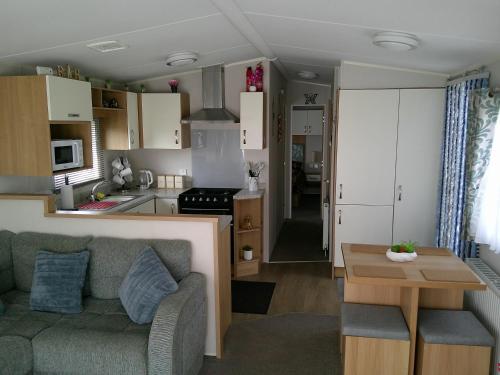 a living room and kitchen with a couch and a table at Mayville Parkstone 6 Berth Central heated in Ingoldmells
