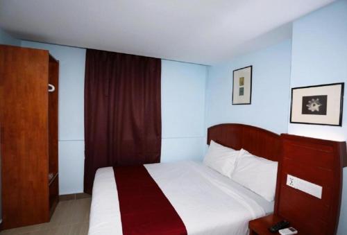 a bedroom with a bed and a wooden cabinet at Orkid Hotel at Bukit Bintang in Kuala Lumpur