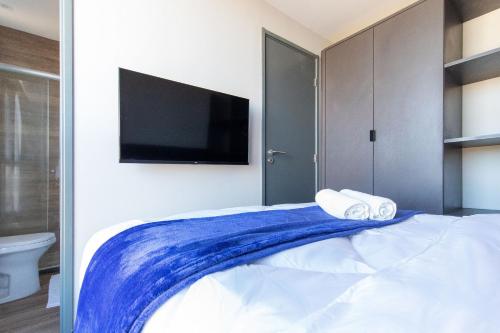 a bedroom with a bed with a tv on the wall at TOLIVE One Housi Recife by Carpediem in Recife