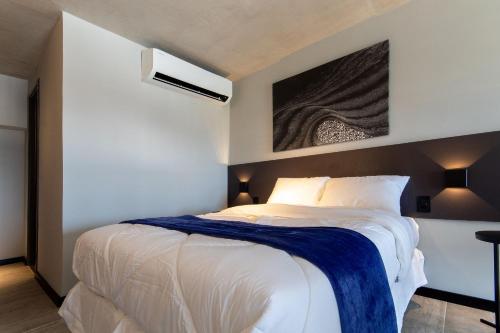 a bedroom with a bed with a blue blanket on it at TOLIVE One Housi Recife by Carpediem in Recife