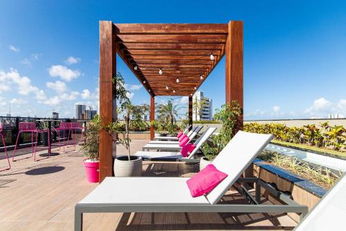 a row of lounge chairs on the roof of a building at TOLIVE One Housi Recife by Carpediem in Recife