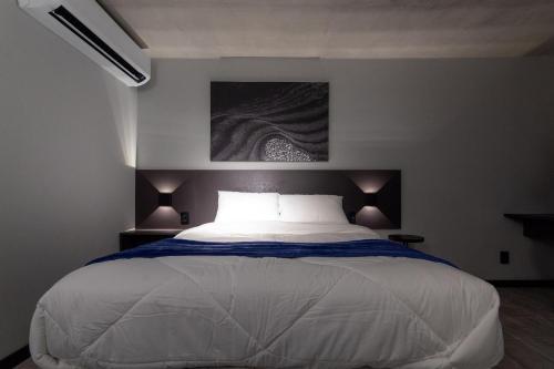 a bedroom with a white bed with a painting on the wall at TOLIVE One Housi Recife by Carpediem in Recife