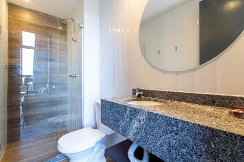 a bathroom with a sink and a toilet and a mirror at TOLIVE One Housi Recife by Carpediem in Recife