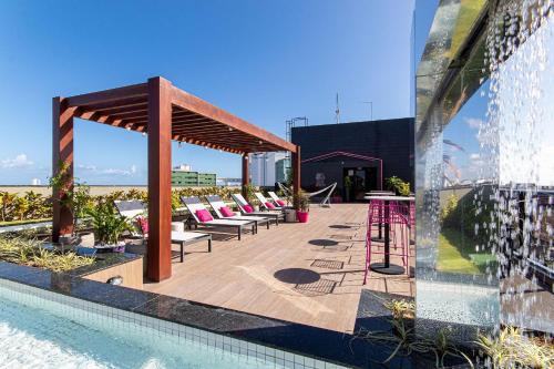 a pool with lounge chairs and a pavilion next to a building at TOLIVE One Housi Recife by Carpediem in Recife
