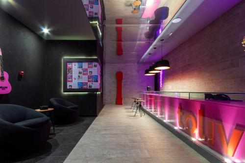 a bar with purple lights and a counter with chairs at TOLIVE One Housi Recife by Carpediem in Recife