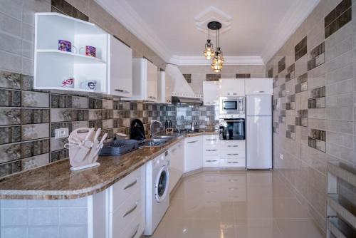 a large kitchen with white cabinets and appliances at Dream Garden Djerba in Djerba