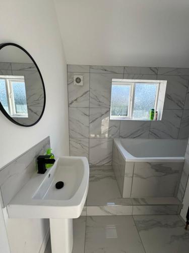 a bathroom with a sink and a tub and a mirror at 3 bedroom Home in chesterfield with front and back gardens in Chesterfield