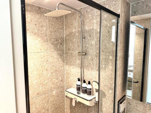 a shower with a glass door with bottles on a shelf at THE DECEMBER STAY Busan Songdo Ocean Terrace in Busan