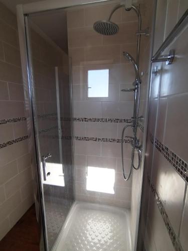une salle de bain avec une douche avec une porte vitrée dans l'établissement Le clos de bourdeilles chambre 3 avec wifi, à Bourdeilles