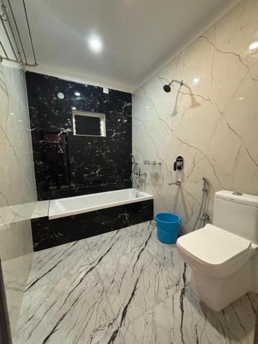 a bathroom with a toilet and a tub and a sink at Chuti Beach Resort in Mandarmoni
