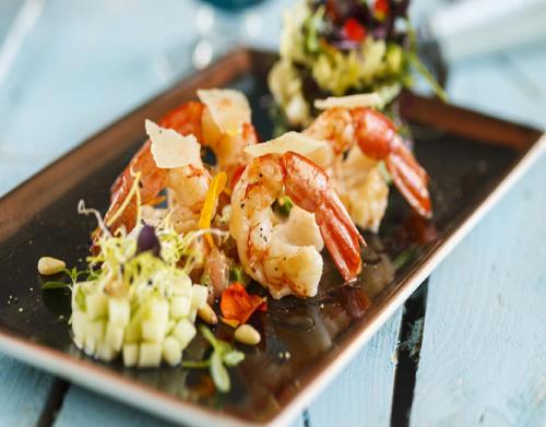 a plate of food with shrimp and vegetables on a table at 2Ciels Boutique Hôtel in Marrakesh