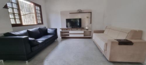 a living room with a couch and a tv at Casa em Ponta Negra in Natal