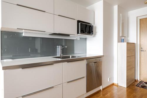 a white kitchen with a sink and a microwave at Hervanta Heat Loft - Ilmainen WIFI in Tampere