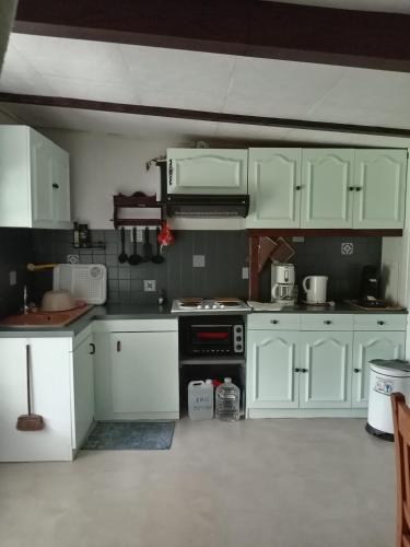 une cuisine avec des armoires blanches et un four à plaques de cuisson dans l'établissement Gîte insolite de L'Escouriou, à Villefranche-Sur-Cher