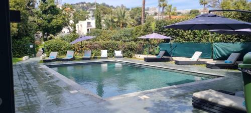 une piscine avec chaises et parasols dans l'établissement Villa Alexandra - Luxury Apartments Jardins d'ARLIAS by Sweett, à Cannes