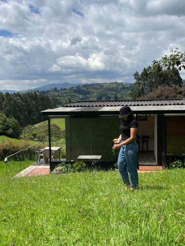 a woman standing in the grass in a field at Cabaña Morada Rachusiju para relajarte y descansar in Tabio