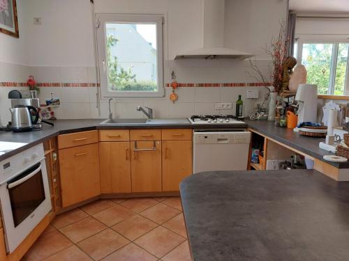 a kitchen with wooden cabinets and a sink and a window at Découvrir le Finistere depuis MA Maison lumineuse calme et ZEN in Landerneau