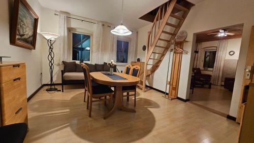 a living room with a table and chairs and a staircase at Ferienwohnungen zur Post - 102 in Weidenberg