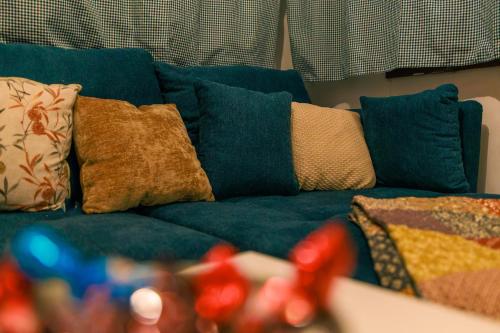 a blue couch with many pillows on it at Honeydew Cottage in camp Terme Čatež in Čatež ob Savi