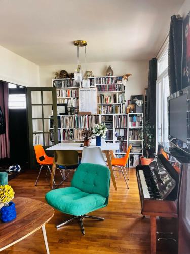 a living room with a table and a green chair at Cyrus House in Le Mans