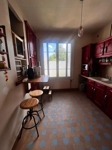 une cuisine avec des placards rouges, une table et un tabouret dans l'établissement Cyrus House, au Mans