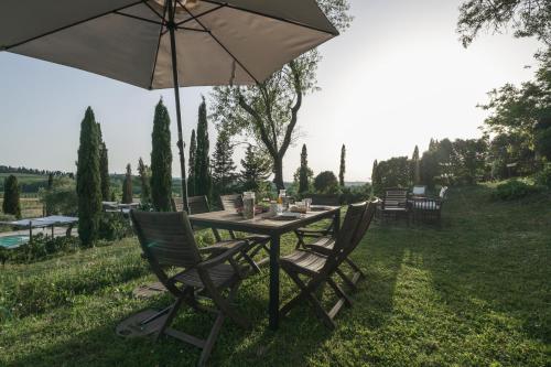 a table with chairs and an umbrella in the grass at Agriturismo La Ca'Solare in Palaia