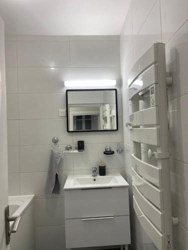 un bagno bianco con lavandino e specchio di Comme à la maison, en Normandie a Gruchet-le-Valasse