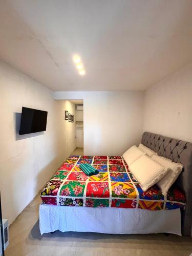 a bedroom with a bed with a colorful blanket at Suite 4 - Village Capixaba in Gravatá