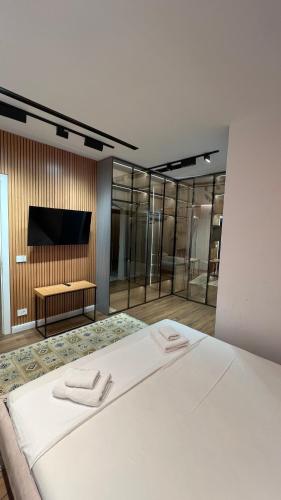 a bedroom with a white bed and a flat screen tv at MIKU Green Coast in Palasë