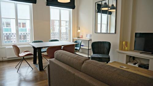 un salon avec un canapé et une table avec des chaises dans l'établissement Little Suite - Alix, à Lille