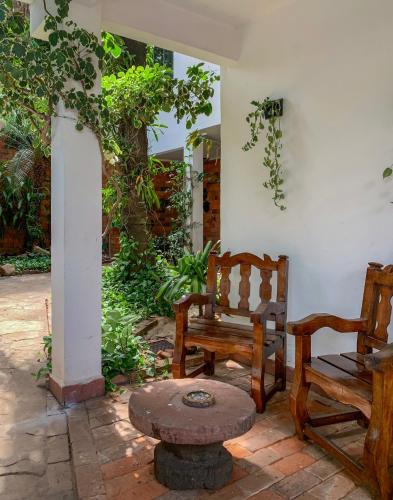 a patio with two wooden chairs and a bench at Casa Eva, rústica y cálida familiar in Asuncion