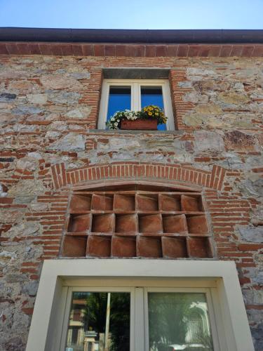 a window on a brick building with a flower pot at La Bottega del Maniscalco in Filettole