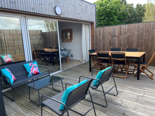 un patio avec des chaises, une table et une terrasse en bois dans l'établissement Maison de vacances ossature bois 2-4 personnes- Saint Gilles Croix de Vie 85800, à Saint-Gilles-Croix-de-Vie