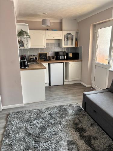a kitchen with white cabinets and a couch in a room at Flat 3 Seaside Haven in Hunstanton