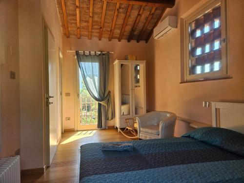 a bedroom with a bed and a window and a chair at La Bottega del Maniscalco in Filettole