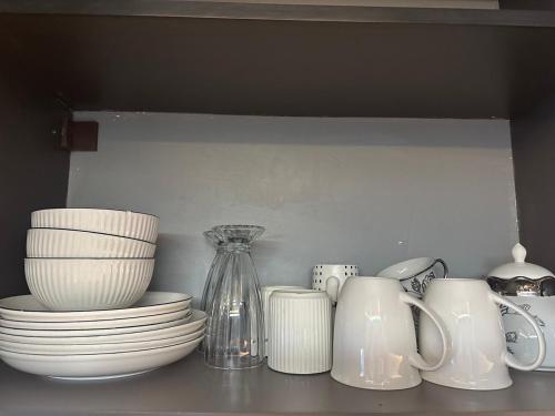 a shelf with plates and cups and a vase at SpeedHome Apartment in Kampala