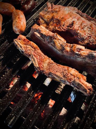 three pieces of meat cooking on a grill at Casa Eva, rústica y cálida familiar in Asuncion