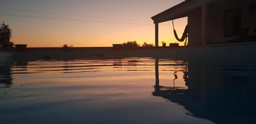 a pool of water with the sunset in the background at Herdade do Vidigal in Montemor-o-Novo