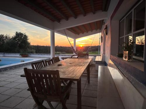 a wooden table and chairs on a patio with the sunset at Herdade do Vidigal in Montemor-o-Novo