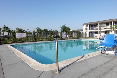 a large swimming pool with a blue chair and a chair at Motel 6-Claremont, CA in Claremont